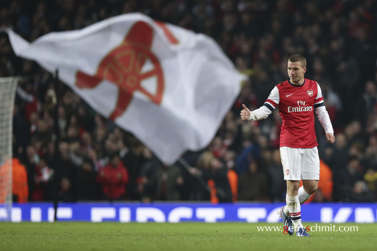 Lukas PODOLSKI lifts his thumb up in front of a Gunners flag after he scored against Bayern Munich