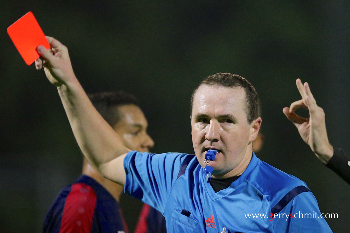 a player reacts after a red card was shown against his team